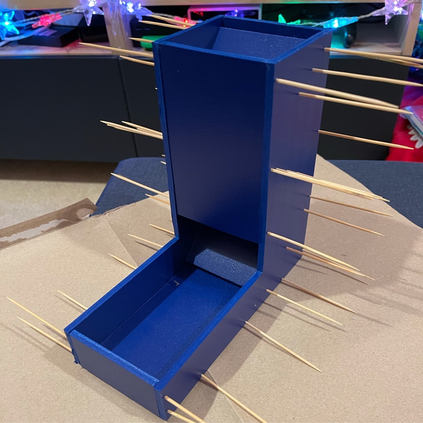 dice tower made of blue foamboard with toothpicks sticking out on the sides